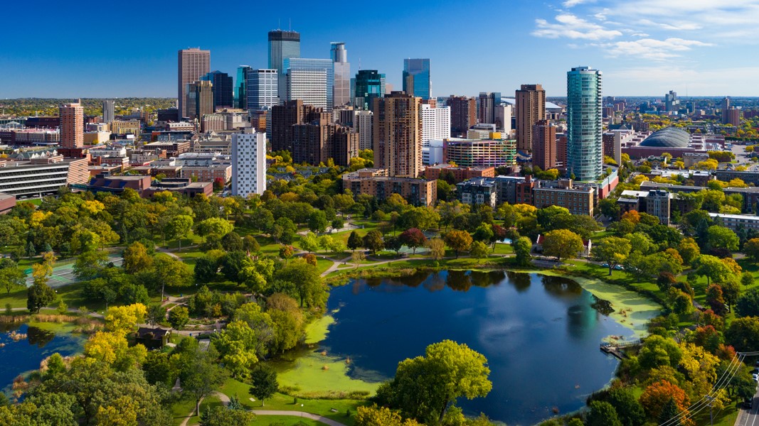 A photo of Minneapolis with a lake and a large park in the foreground
