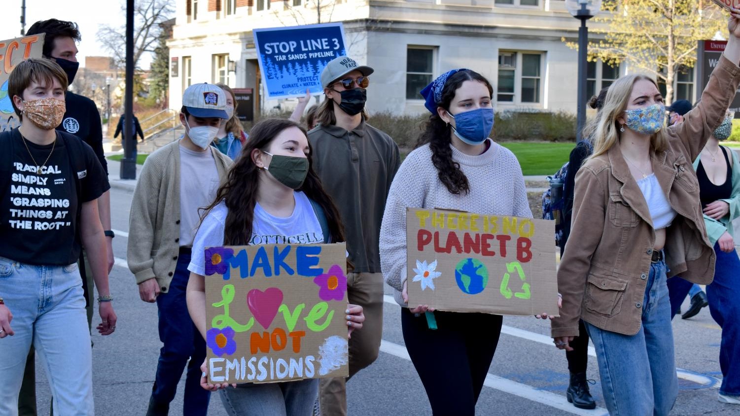 A photo of several students wearing face masks and holding environmental protest signs