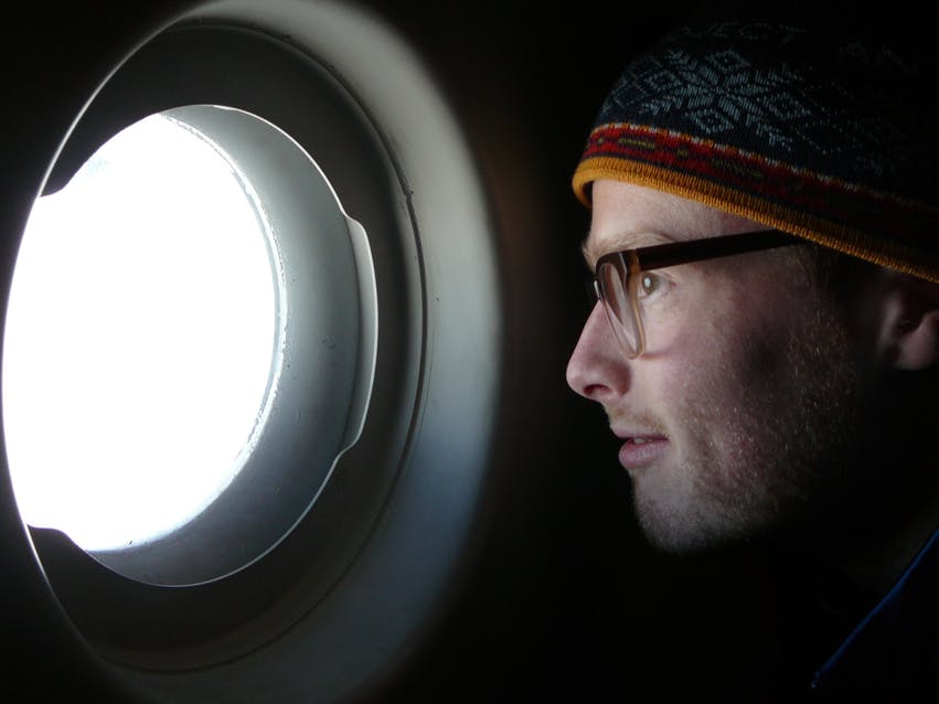A photo of Peter Neff looking out a round aircraft window
