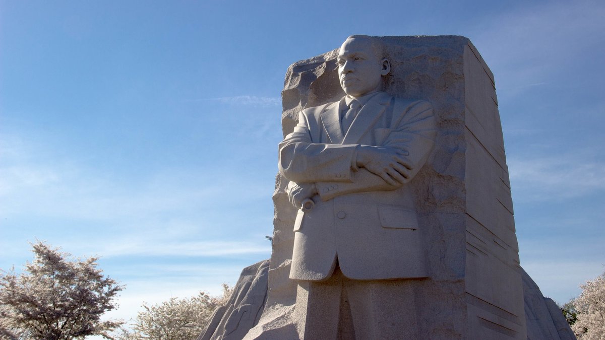 A photo of a monument dedicated to Dr. Martin Luther King, Jr. He is carved into white stone, standing with arms folded. Photo by Geoff Alexander. 