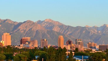 A photo of the Salt Lake City skyline and the Wasatch Range lit by the sunset; photo by Garrett on flickr https://flic.kr/p/bjxDUJ