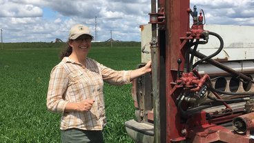A photo of Jess Gutknecht in the field next to machinery