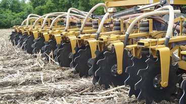 A photo of a field being strip tilled by a large machine