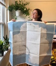 A photo of Julia Andreasen holding a large map of Antarctica